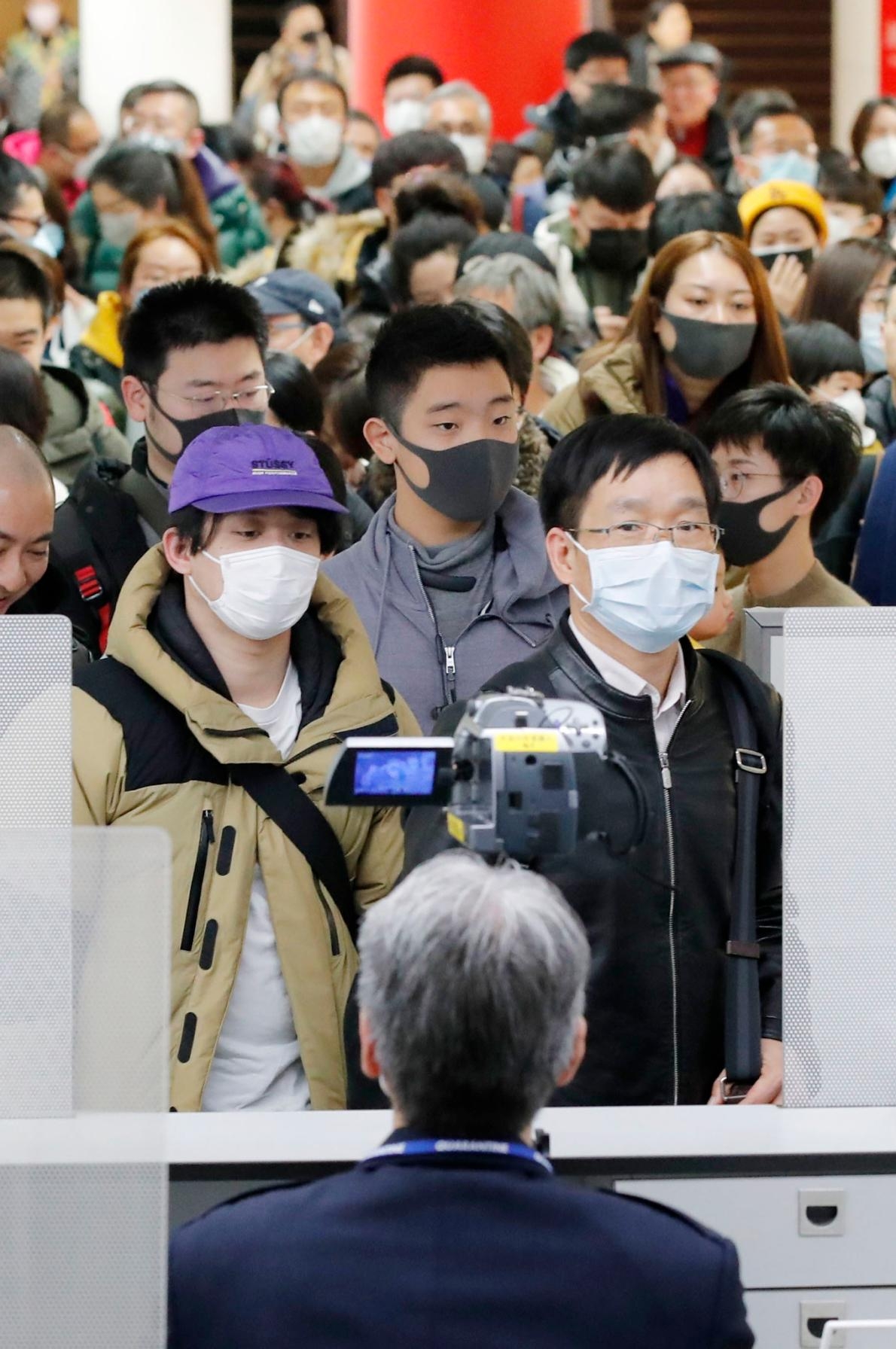 2020年1月23日，從新型冠狀病毒肺炎爆發起源地中國武漢飛抵日本的旅客，正通過東京成田機場的檢疫。前景中架設的是溫度監控儀器，用以檢查旅客的體溫。PHOTOGRAPH BY KYODO VIA AP IMAGES
