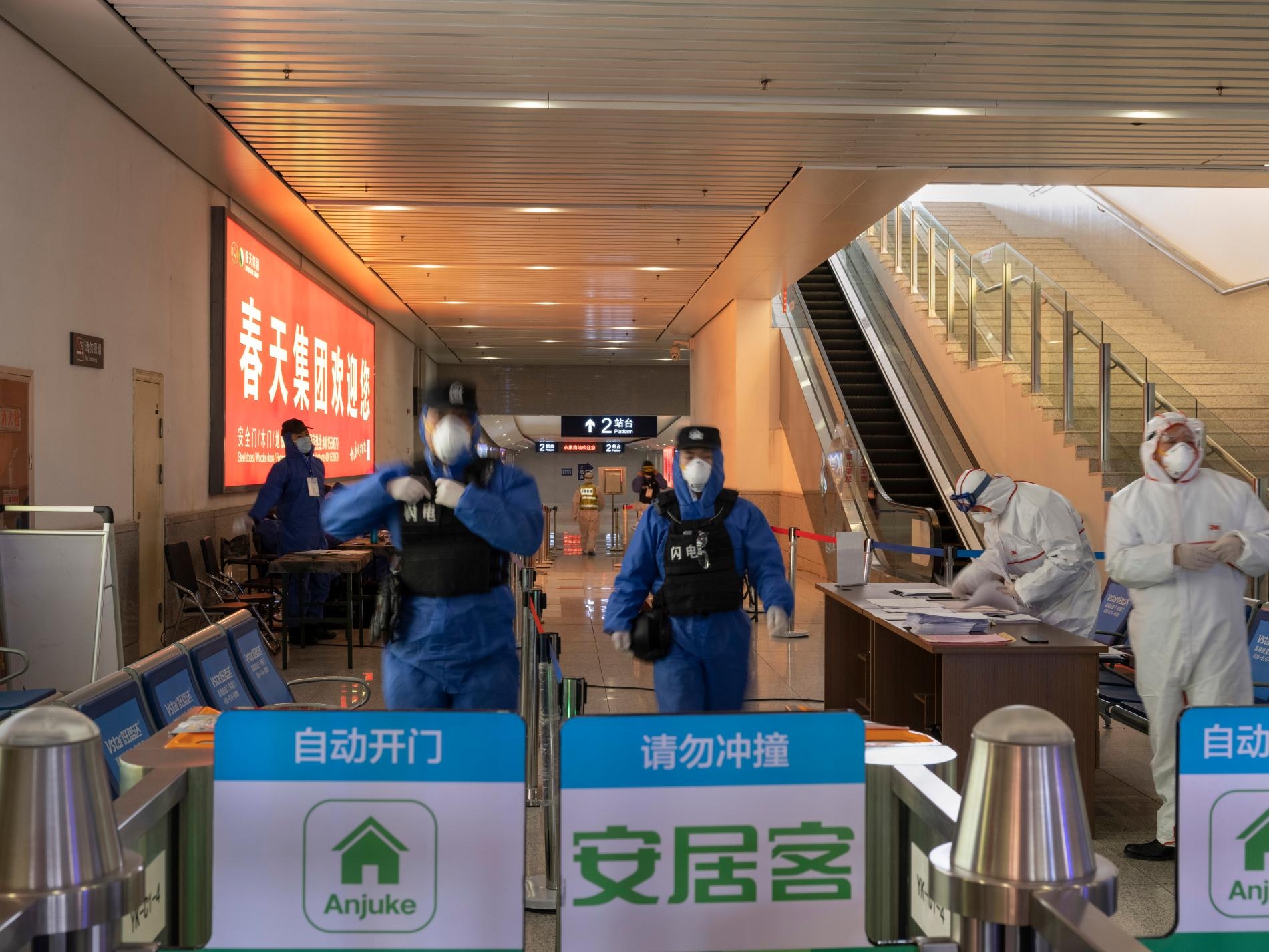 2月9日，警察與衛生人員守在高鐵站其中一處出口。全國各地還在營運的車站，每個出入口都要幫旅客量體溫。旅客若是發燒超過攝氏37.3度，就要被帶到健康機構。PHOTOGRAPH BY ROBAN WANG, NATIONAL GEOGRAPHIC