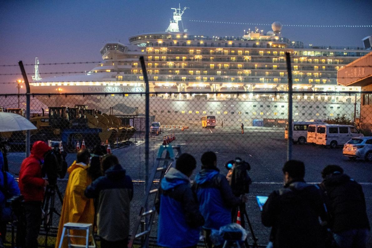2020年2月16日，一輛巴士駛近停靠在日本東京南方橫濱港內大黑遊艇碼頭的鑽石公主號（Diamond Princess）。這艘遊輪上有幾十名遊客的冠狀病毒篩檢呈陽性反應。 PHOTOGRAPH BY ATHIT PERAWONGMETHA, REUTERS 