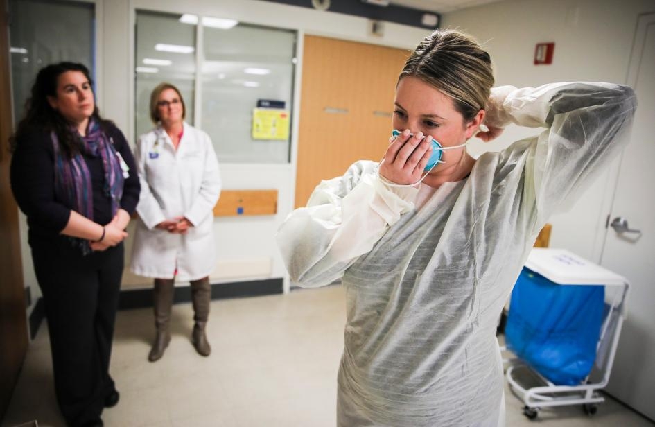 波士頓的麻省總醫院（Massachusetts General Hospital）於2020年2月27日準備應對可能激增的冠狀病毒病患時，凱倫．史密斯（Kaylen Smith）示範如何穿戴在處置感染性疾病患者時所需的防護裝備。PHOTOGRAPH BY ERIN CLARK, THE BOSTON GLOBE VIA GETTY IMAGES