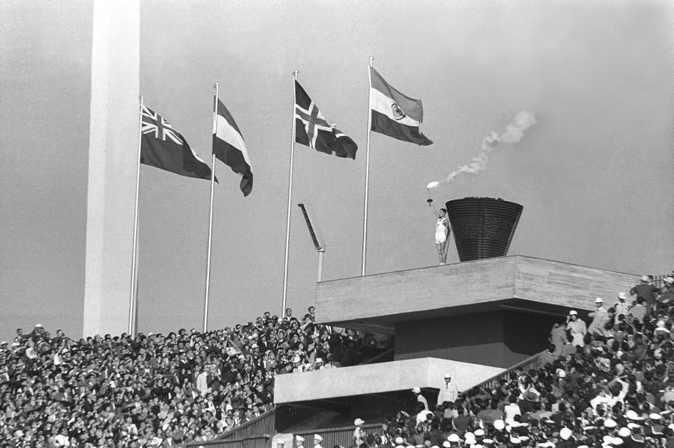傳遞奧運聖火最後一棒的阪井義則在1964年東京奧運開幕儀式上高舉聖火。這是日本第一次主辦奧運；雖然東京曾在1940年獲得奧運主辦權，卻因備戰二次世界大戰而被迫取消。PHOTOGRAPH FROM SANKEI ARCHIVE, GETTY