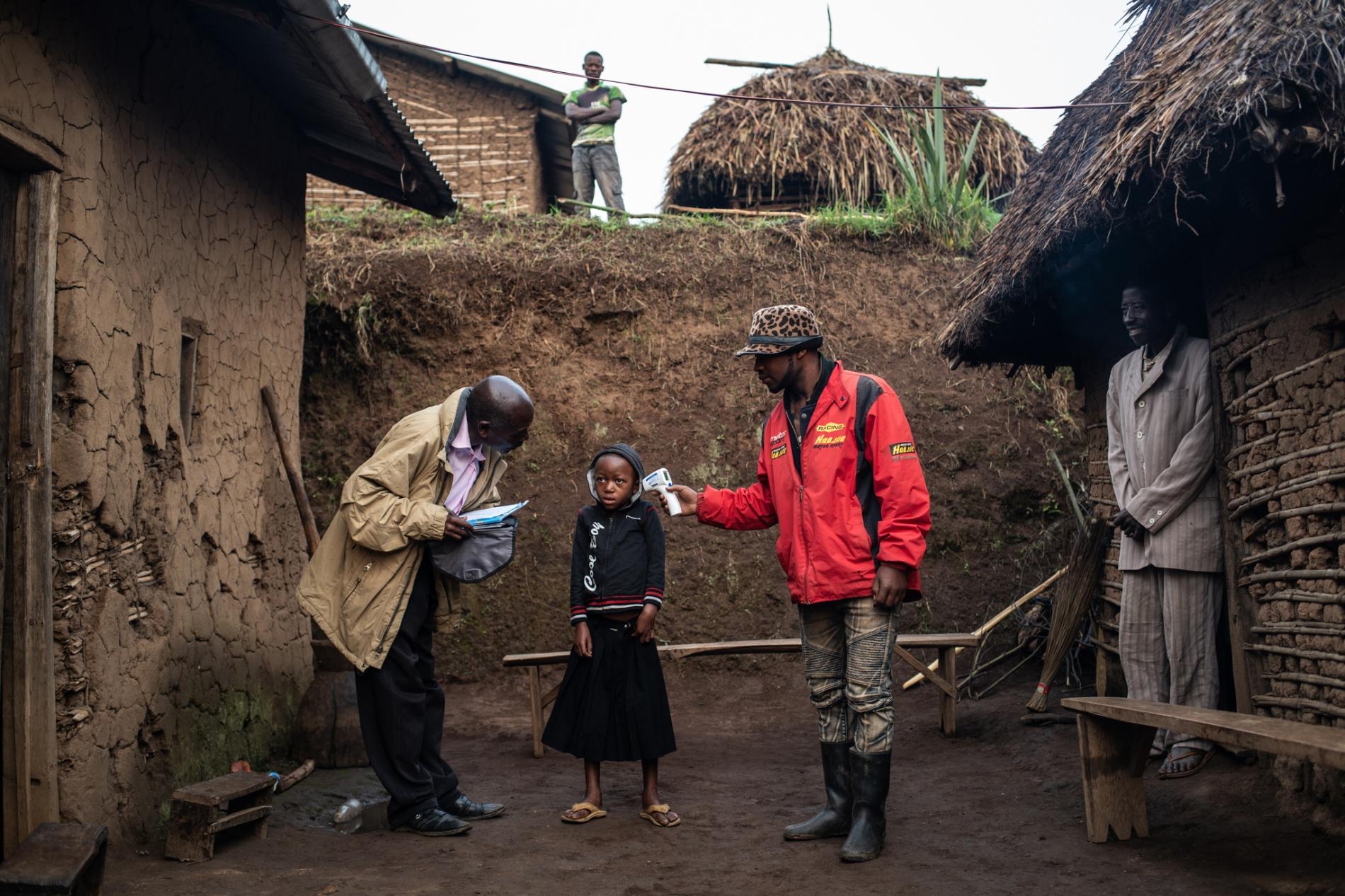 2019年，一個WHO團隊在瓦亞納鎮為7歲的康福美．馬斯卡．穆格漢伊拉（Confirme Masika Mughanyira）檢查體溫，該鎮位於DRC布滕博兩小時車程處。因為伊波拉疫情，康福美失去了雙親、哥哥及妹妹。身為家裡唯一一名倖存者，她現在由親戚照料。PHOTOGRAPH BY NICHOLE SOBECKI