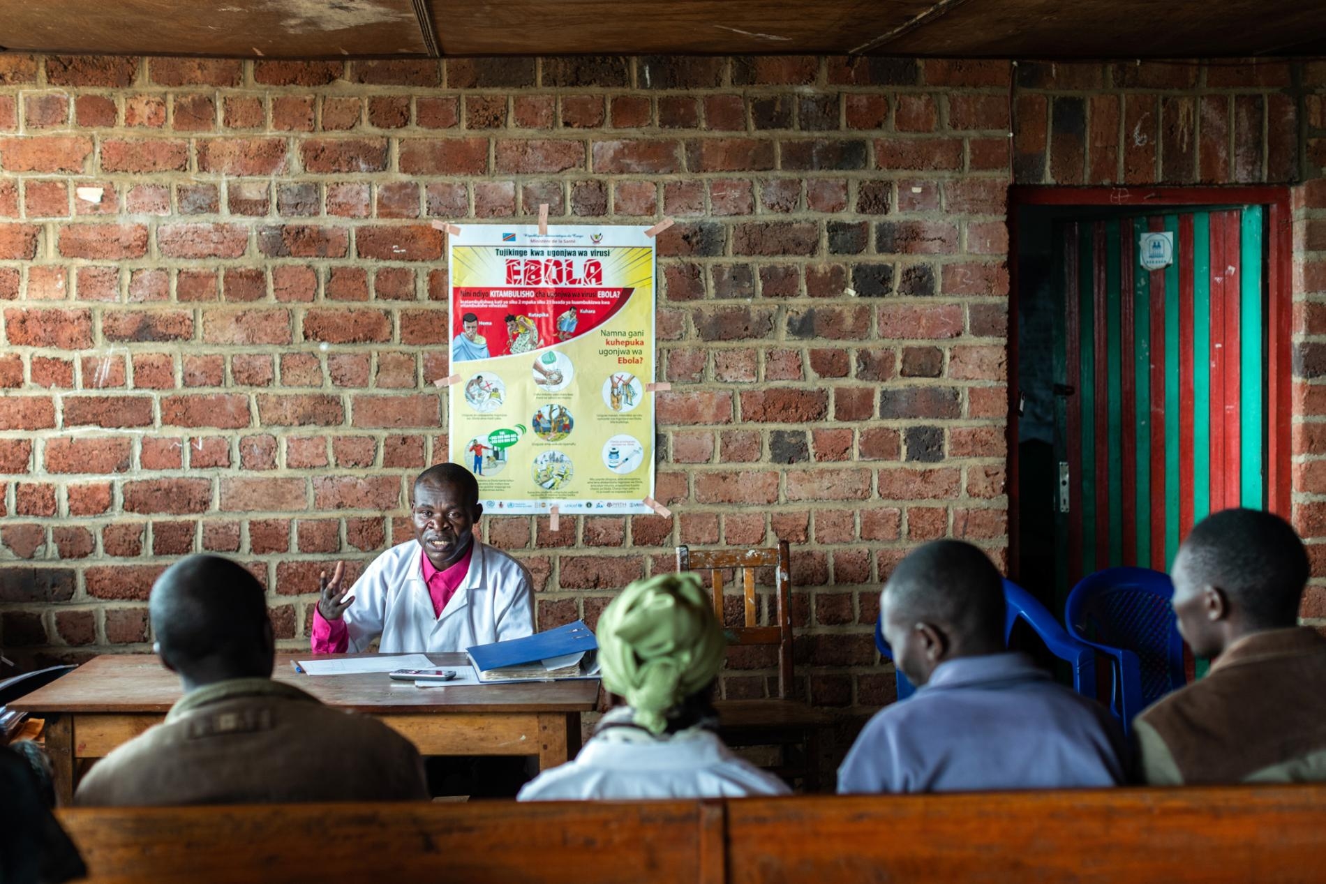 2019年3月4日，在DRC炯多鎮外，當地衛生團隊與社區醫療外展人員在一天的實地工作後互相交流，討論集體進展與面臨的挑戰。WHO已經在大城市外，像炯多這樣的區域設立數個伊波拉反應營，小型群聚的伊波拉病患會出現在這種區域。炯多位於布滕博往維龍加方向的1.5小時車程處。PHOTOGRAPH BY NICHOLE SOBECKI