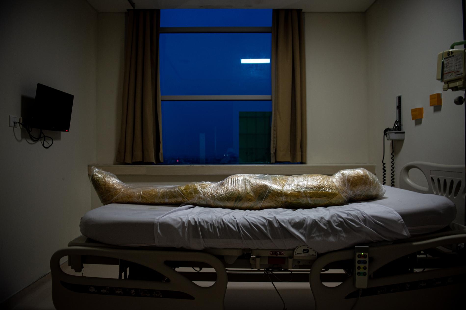疑似COVID-19罹難者的遺體放在印尼的一間醫院。該病患死亡後，護理師用層層塑膠膜包裹遺體並塗抹消毒劑，以預防病毒傳播。PHOTOGRAPH BY JOSHUA IRWANDI