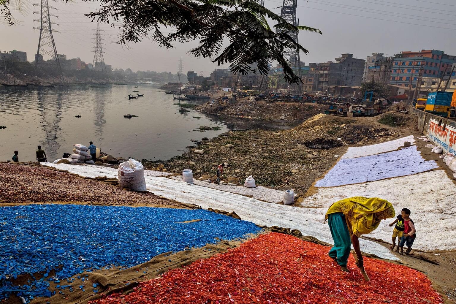 彩色塑膠碎片經過人工收集、清洗和分類後，堆放在河岸上曝曬。達卡市和周遭地區約有12萬人從事這種非正式資源回收業。攝影：藍迪．奧森 RANDY OLSON