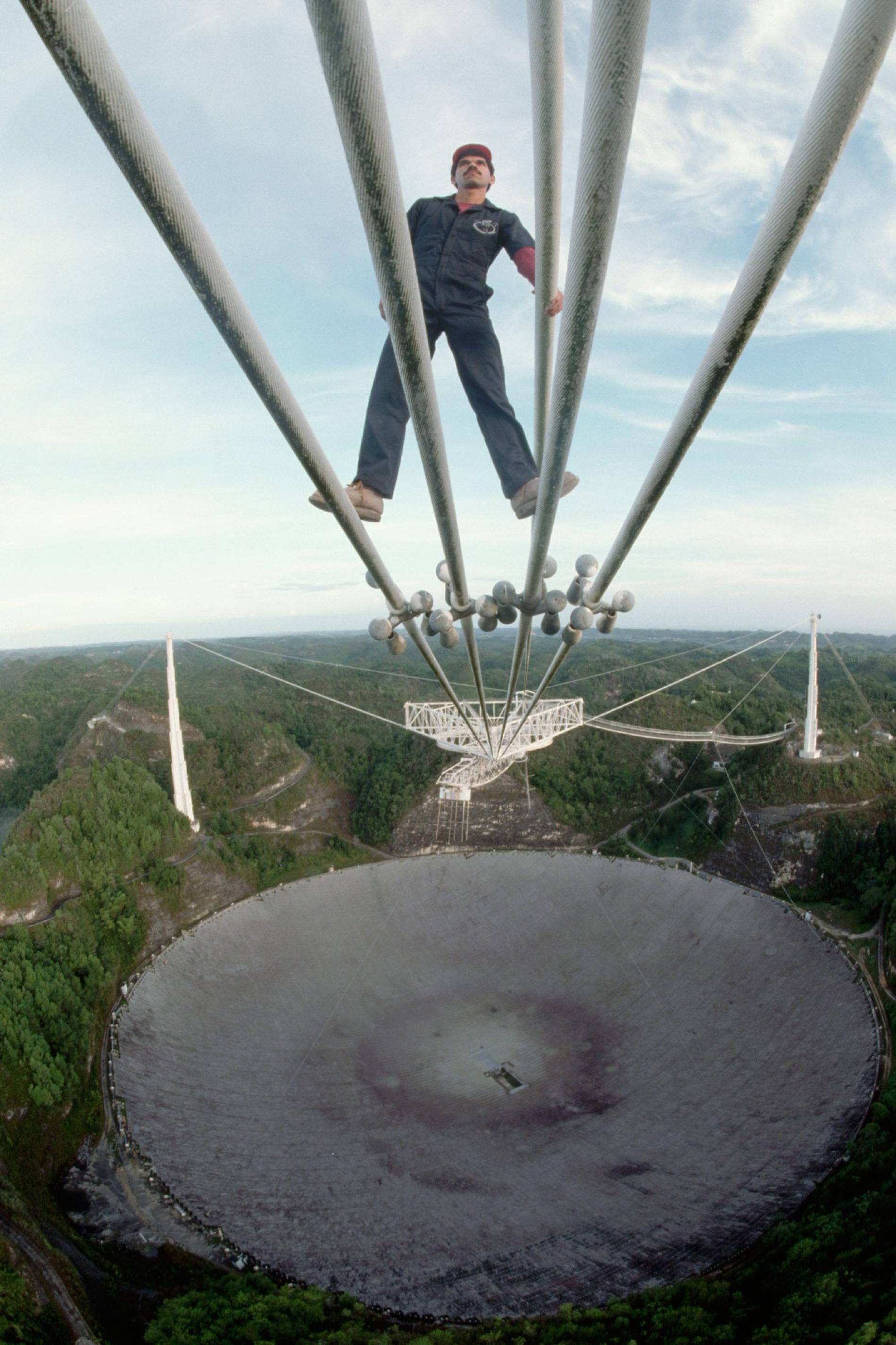 1989年，技術員路易斯．埃雷迪亞（Luis Heredia）正在阿雷西博天文臺檢查將接收器懸掛在電波望遠鏡天線上的鋼纜。PHOTOGRAPH BY ROGER RESSMEYER/CORBIS/VCG VIA GETTY IMAGES