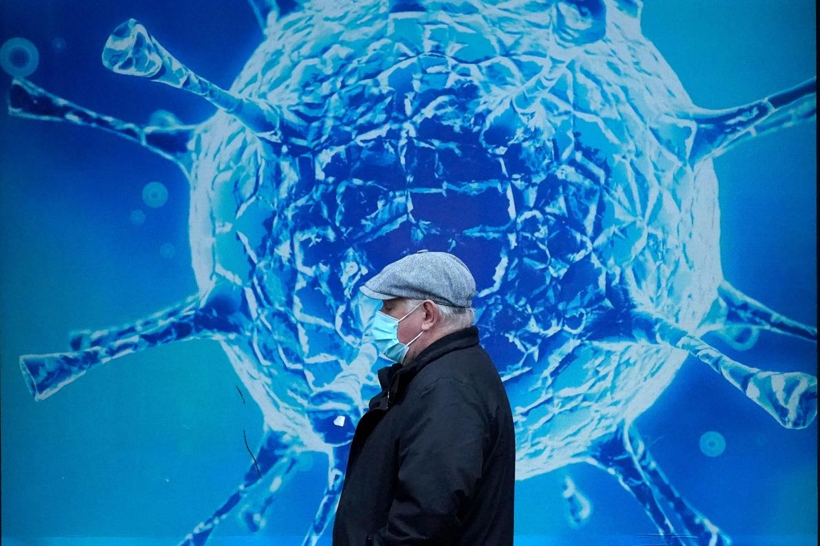 2020年11月24日英國奧爾德姆，一名戴著防護口罩的男子走過奧爾德姆區域科學中心外的病毒示意圖。愈來愈多國家發現COVID-19復發病例，而這種現象顯示，從SARS-CoV-2冠狀病毒康復，並不是疫情大流行如火如荼時無視健康規範的藉口。PHOTOGRAPH BY CHRISTOPHER FURLONG, GETTY IMAGES 