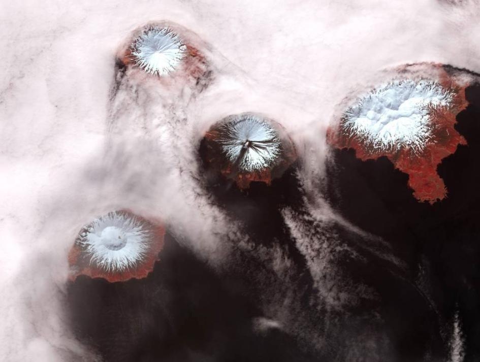 阿拉斯加的四山群島其實擁有六座火山，其中幾座如圖中所示。不平靜的克里夫蘭山（位於中間）是阿留申群島中最活躍的火山。研究這個島鍊的火山災害對上方頻繁的空中交通至關重要。「我們講說它是非常偏僻的地區，它真的是，不過當你往上到達九千多公尺的高空時，每天就會有（數萬）人從這裡通過。」地球物理學家約翰．包爾說。PHOTOGRAPH BY NASA
