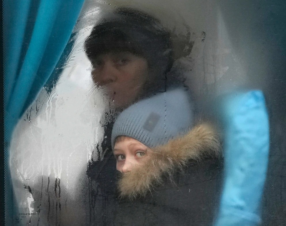 2/24那天，一位女性和小孩要離開烏東的北頓內次克時，從巴士的窗子往外望。烏克蘭爆發的戰爭可能會造成大量死傷、難民危機，並在世界各地造成混亂的影響，衝突專家說。PHOTOGRAPH BY VADIM GHIRDA, AP