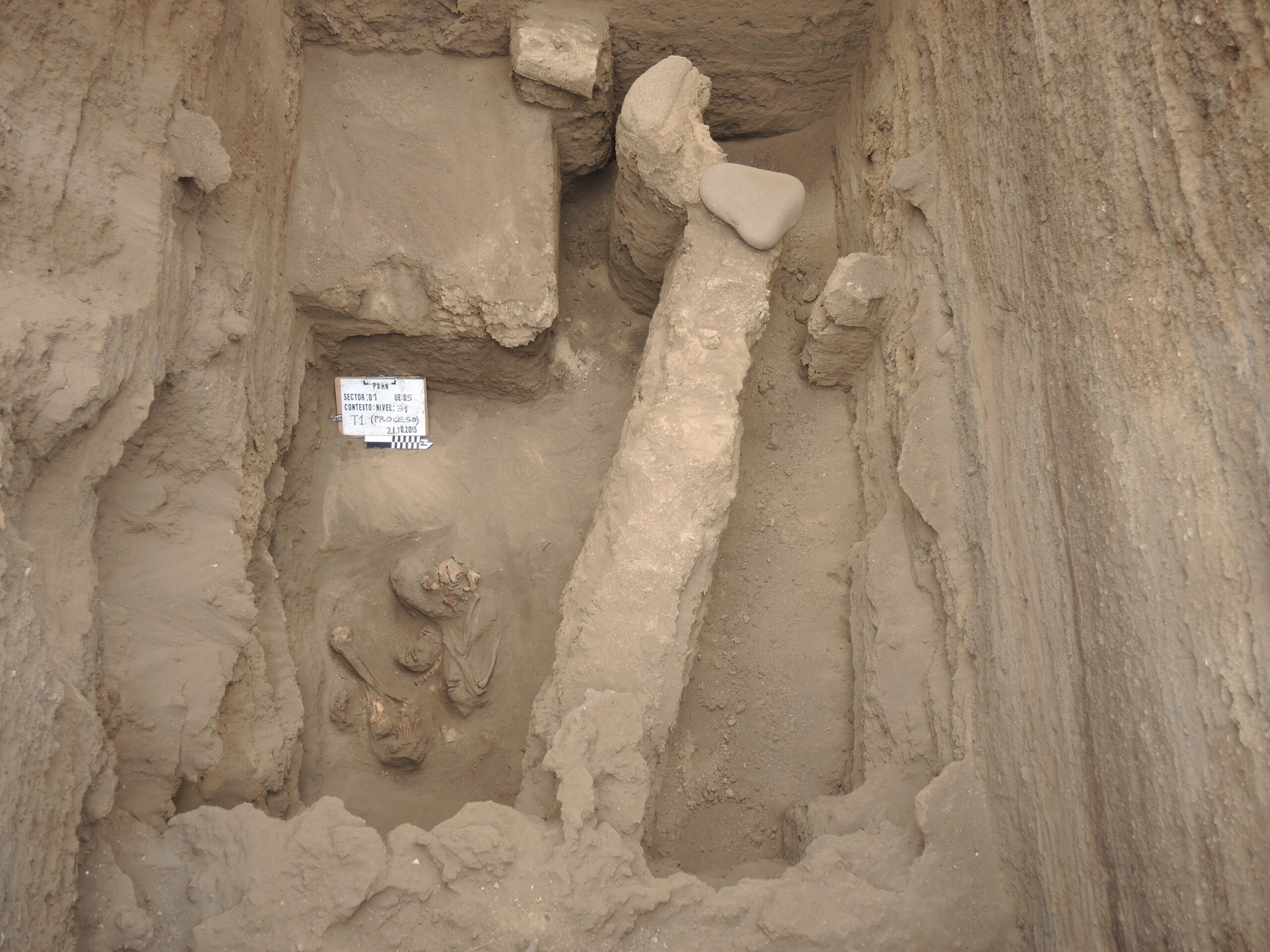 第三居住階段（聚落展開公共建築計畫）地層中，發現一具女性骸骨（左下）、殘存的公共建築泥磚牆基。為了方便發掘人骨，上方的牆基、火煻、石頭已先移除。 圖｜陳珮瑜 