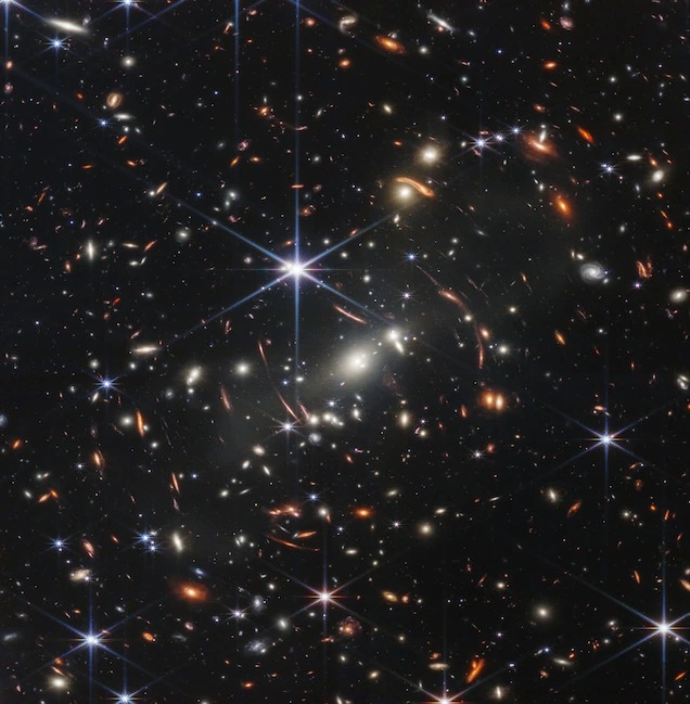韋伯太空望遠鏡拍攝的第一張深空影像，顯示被前景星系團放大的宇宙初期星系。IMAGE BY NASA, ESA, CSA, AND STSCI