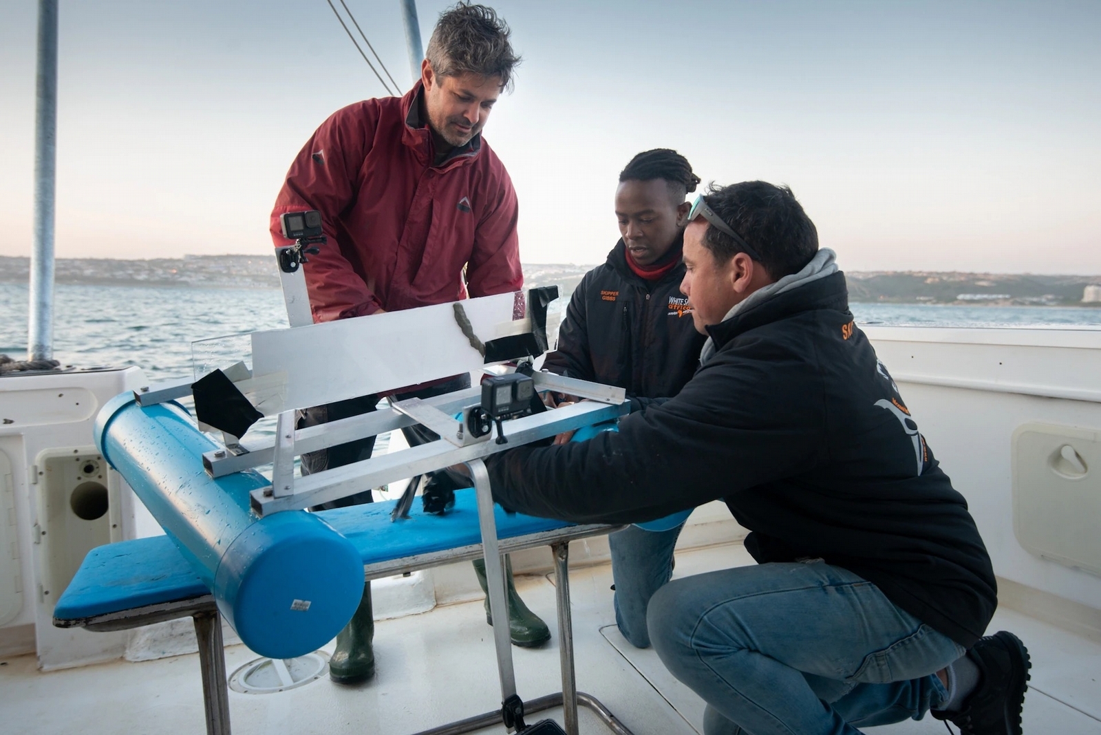 萊恩．強生（Ryan Johnson）、吉布斯．庫古魯和一位同事在檢查即將下水的浪橇，這將作為鯊魚在實驗中的休息之處。PHOTOGRAPHS BY FIONA AYERST, NATIONAL GEOGRAPHIC