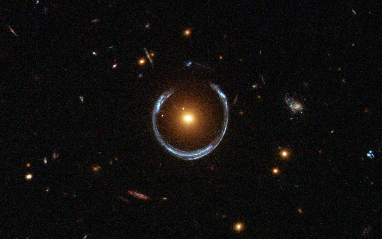 紅色星系做為遙遠後方藍色星系的重力透鏡，將其光線扭曲成弧形。圖片來源：ESA/Hubble and NASA