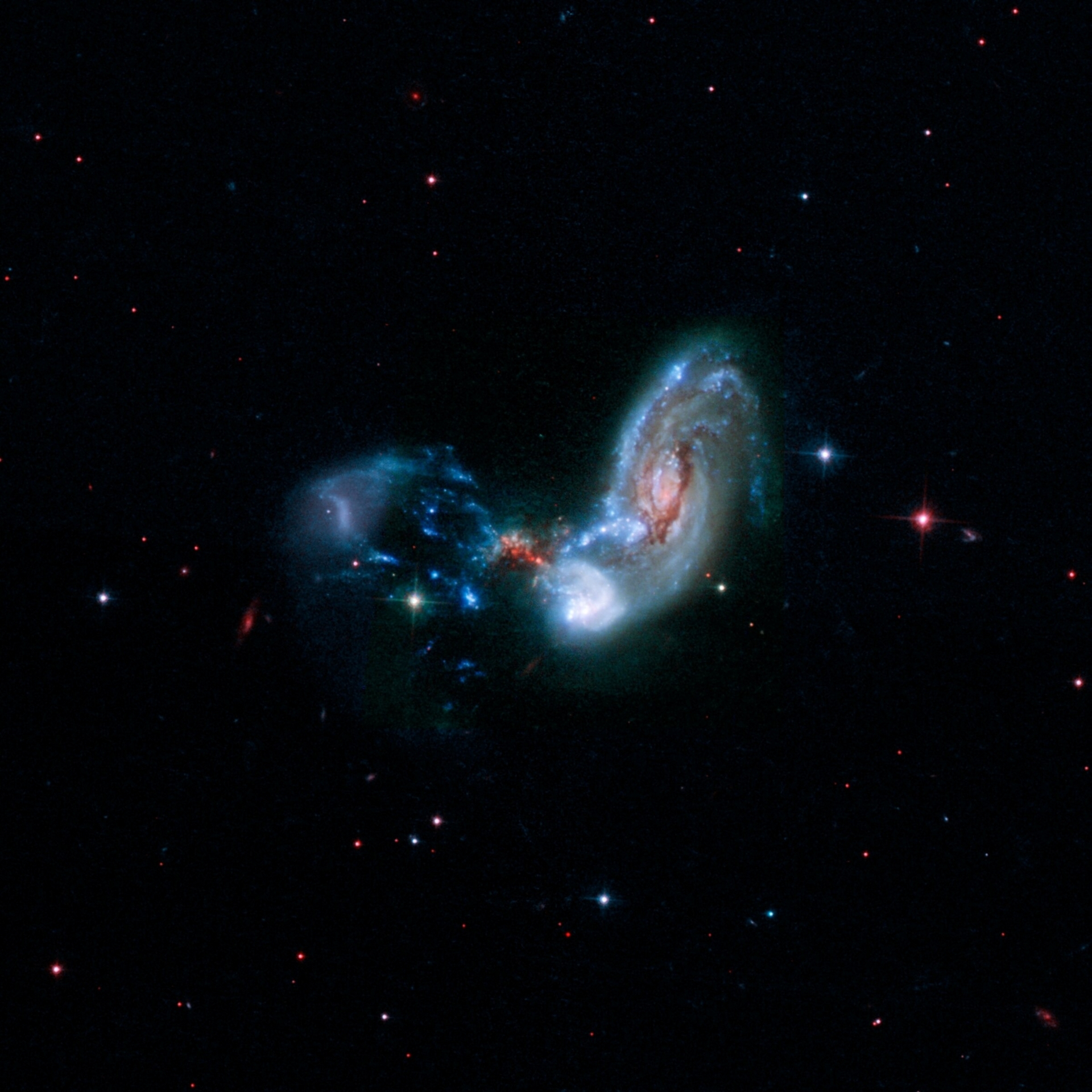 合併星系可能呈現許多令人著迷的形狀。這些合併星係稱為II Zw 096，影像中央附近的紅色斑點暗示此處是壯觀的恆星形成遽增位置。PHOTOGRAPH BY NASA, CALTECH, H. INAMI (HIROSHIMA UNIVERSITY) 