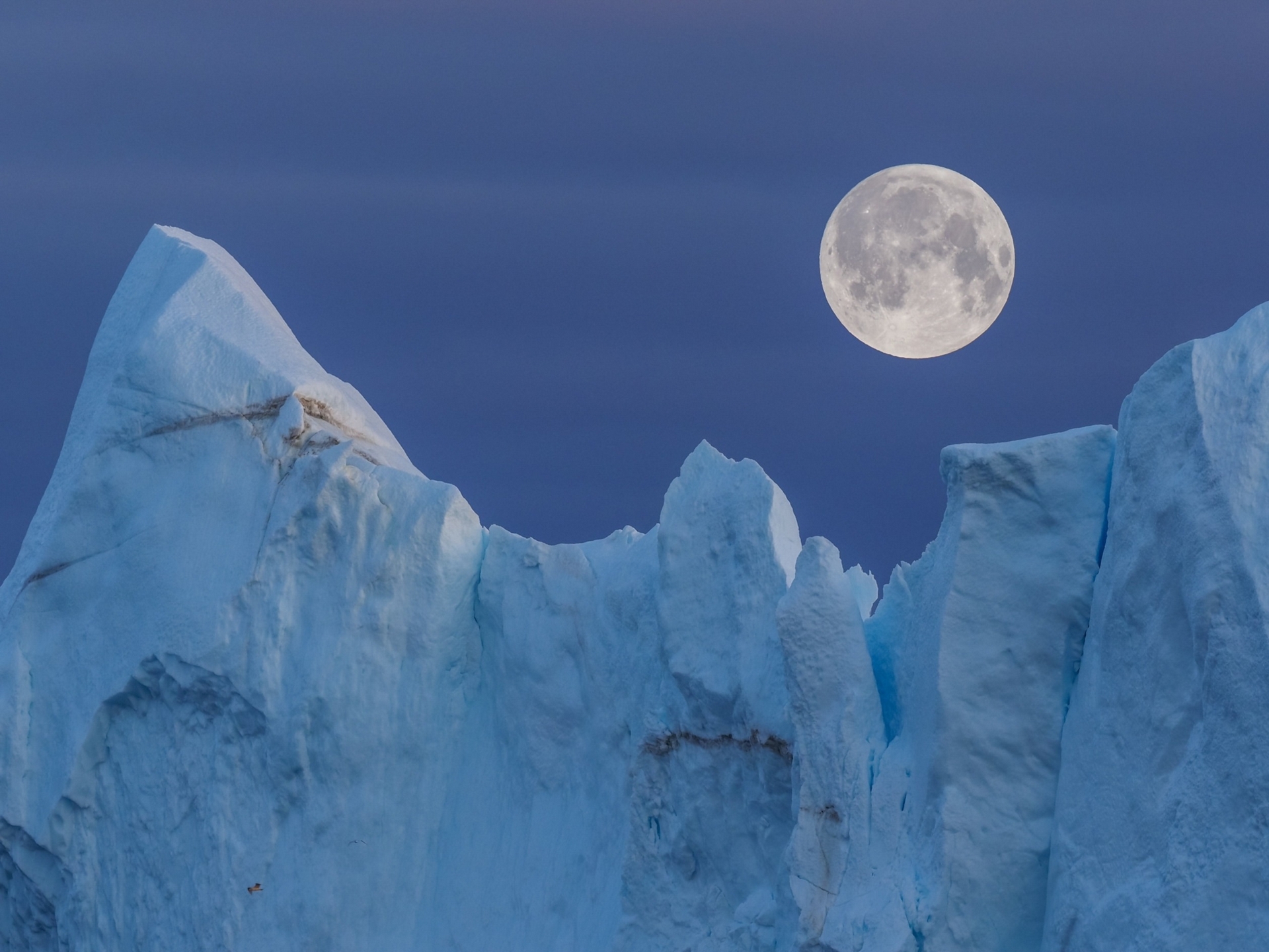格陵蘭島迪斯科灣（Disko Bay）冰山上方的滿月。科學家研究阿波羅（Apollo）計畫期間帶回的月球樣本，發現月球地殼的形成時間比先前的推測至少早4000萬年。PHOTOGRAPH BY MARCIN DOBAS, NAT GEO IMAGE COLLECTION