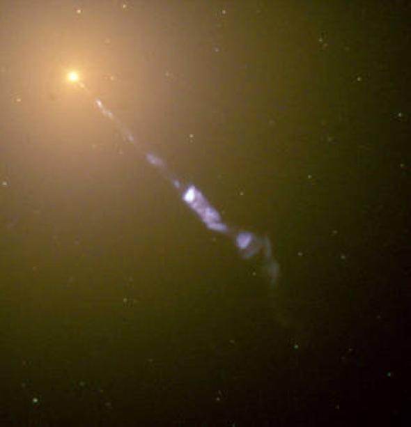 M87星系的中心閃耀著一個巨大的宇宙探照燈：從黑洞向外噴射出的次原子粒子流的速度接近光速。在這張哈伯太空望遠鏡所拍攝的影像中，藍色的噴流與M87星系中恆星和星團所發出的黃色光芒形成強烈的對比。 PHOTOGRAPH BY NASA AND THE HUBBLE HERITAGE TEAM (STSCI/AURA) 